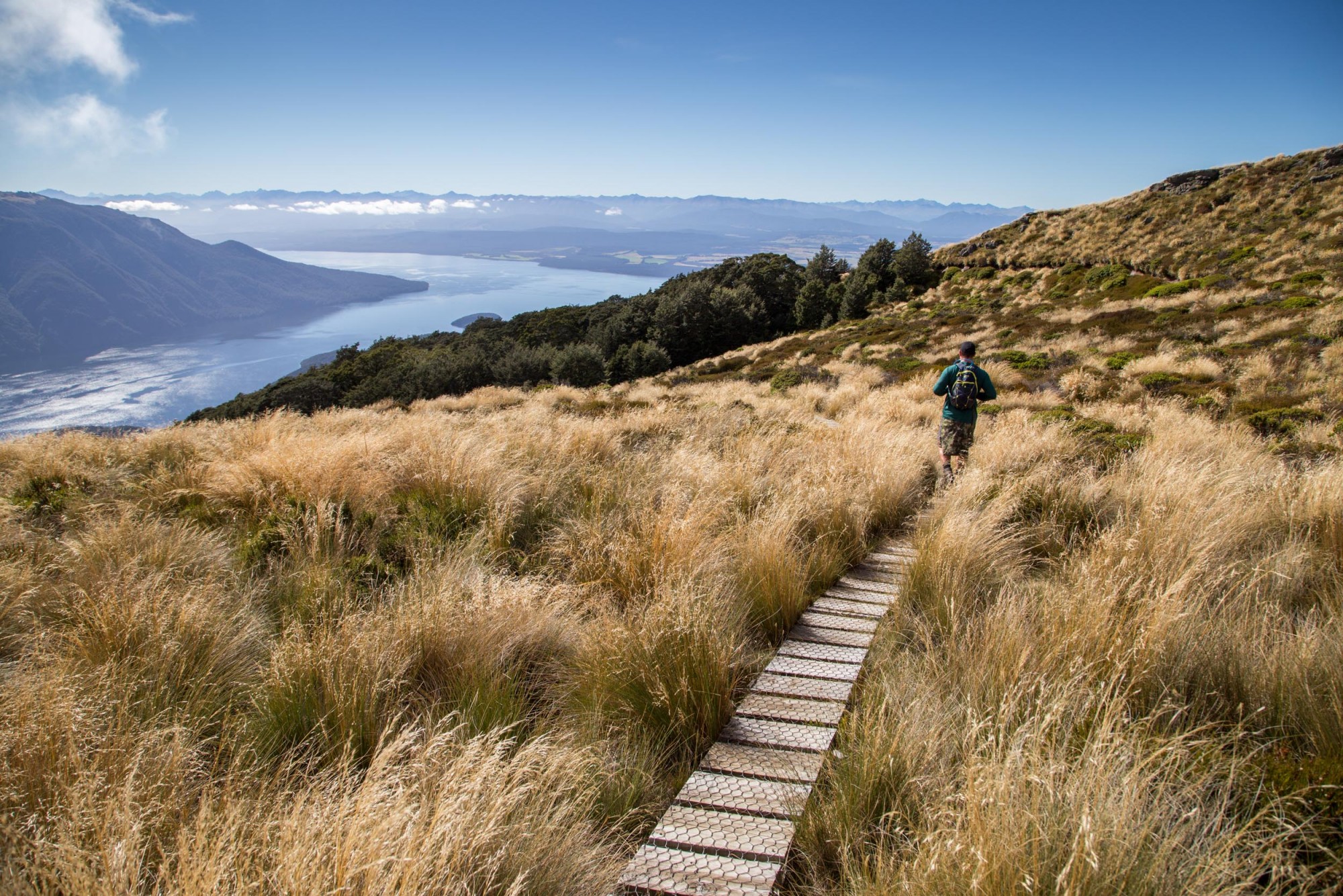 Explore around Luxmore Hut after your helicopter ride Person tramping in mountains above large lake